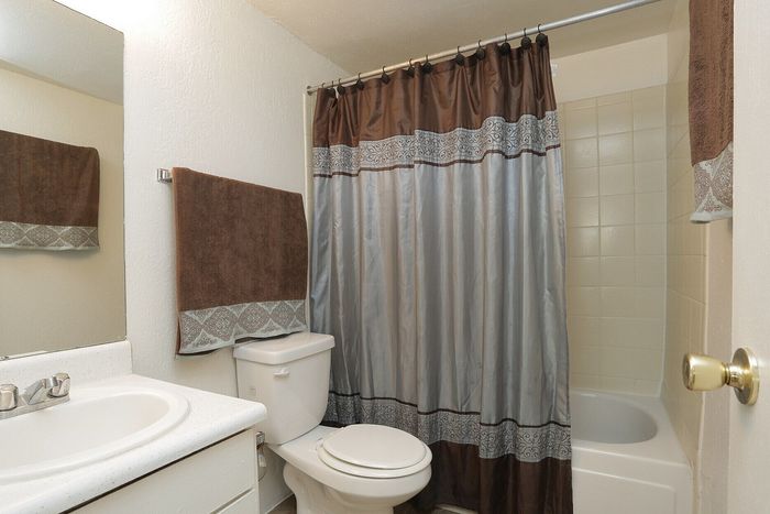 Elegant bathroom featuring a pristine white vanity, contemporary faucet, and a stylish brown and gray shower curtain.