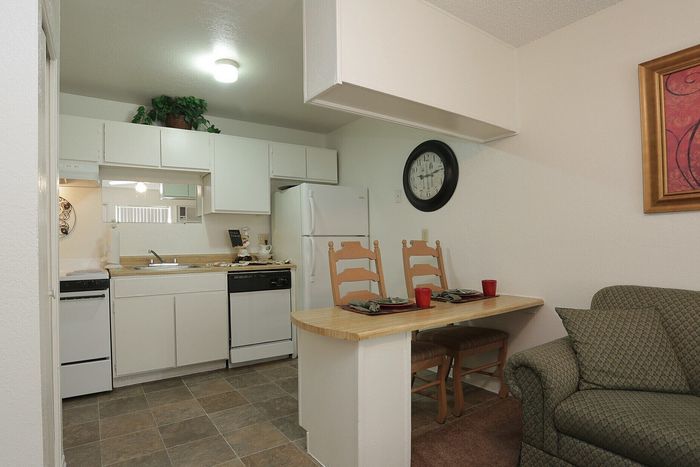 Cozy apartment kitchen and dining area with white cabinetry, modern appliances, and intimate seating for two.