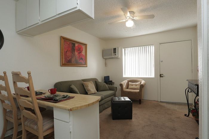 Cozy living room with elegant decor, including a plush sofa, armchair, and intimate dining area with two chairs, enhanced by warm lighting and stylish wall art.
