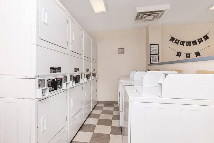 Bright and inviting laundry room featuring modern stacked washers and dryers against a checkered floor design.
