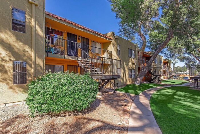 Charming apartment exterior with vibrant greenery, inviting stairways, and well-manicured pathways.