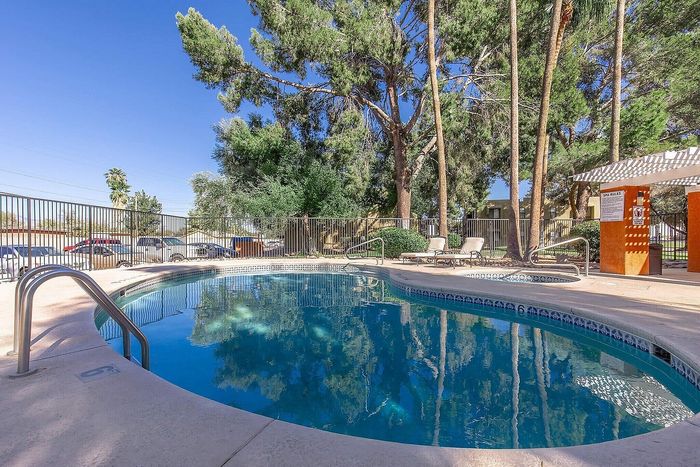 Inviting outdoor pool area with lush trees and modern lounging facilities, perfect for relaxation and enjoyment.