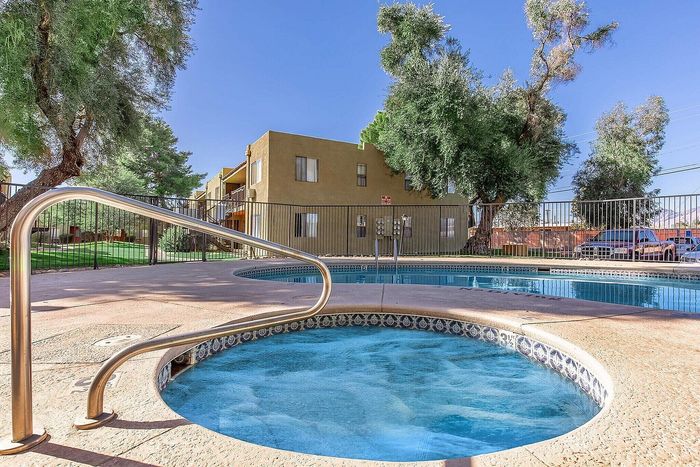 Inviting outdoor area featuring a sparkling hot tub and pool surrounded by lush greenery in a tranquil apartment complex.