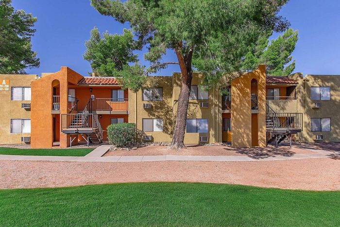 Charming apartment complex showcasing vibrant exterior colors, lush green landscaping, and modern architectural design under a bright blue sky.