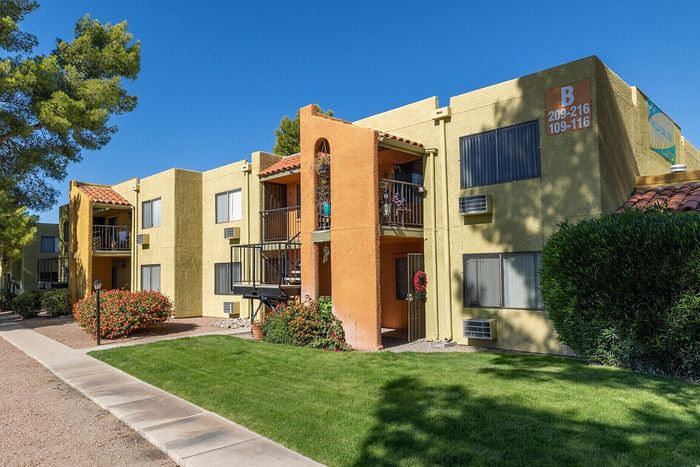 Charming apartment complex with sunny balconies, vibrant landscaping, and lush green surroundings.