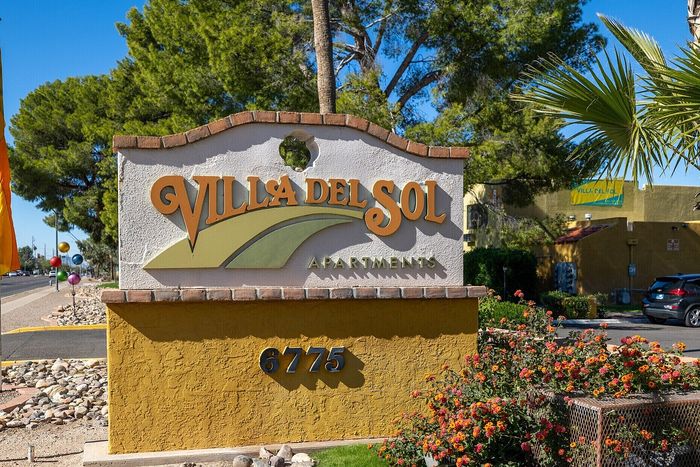 Inviting Villa Del Sol Apartments sign amidst lush greenery and vibrant flowers, showcasing a welcoming community atmosphere.