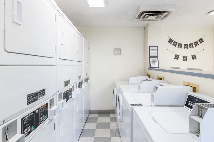 Bright and spacious laundry room with modern stacked washers and dryers, perfect for convenient apartment living.