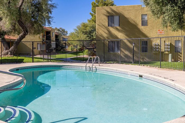 Inviting outdoor pool area surrounded by lush greenery, offering a perfect relaxation spot in a charming apartment community.