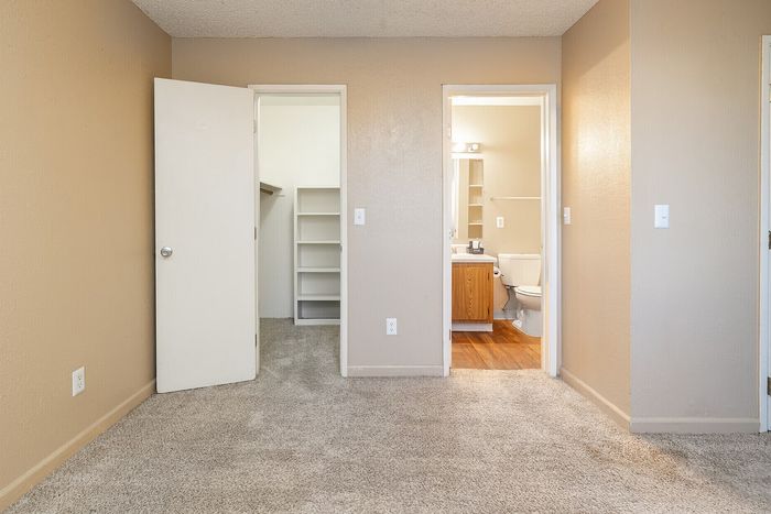 Inviting bedroom with plush carpet, featuring an ensuite bathroom and a spacious walk-in closet.