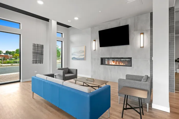 Contemporary living room with sleek fireplace, vibrant blue sofa, modern armchairs, and large windows offering abundant natural light.