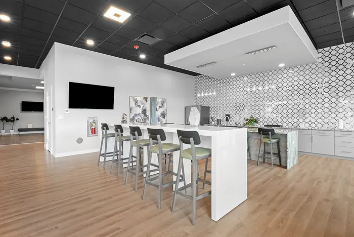 Contemporary open-plan kitchen and dining area featuring a sleek breakfast bar, stylish bar stools, and modern tiled backsplash, perfect for entertaining.