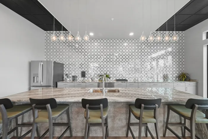 Elegant modern kitchen featuring a large marble island, sleek stainless steel appliances, and stylish pendant lighting.