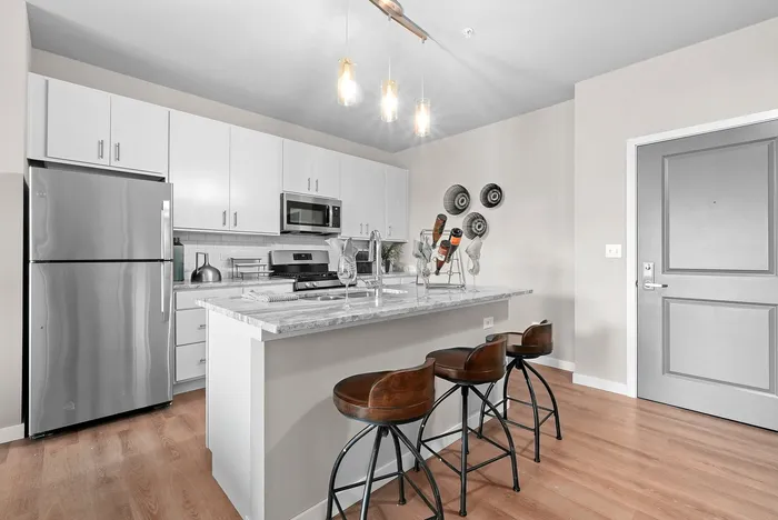 Modern kitchen featuring sleek stainless steel appliances, elegant white cabinetry, and a stylish countertop island with bar seating.