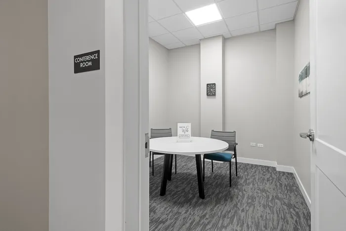 Modern conference room with sleek round table and comfortable chairs, featuring stylish decor and bright lighting.