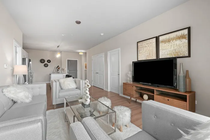 Elegant living room with plush gray sofas, a modern TV setup, and chic decor, exuding comfort and style.