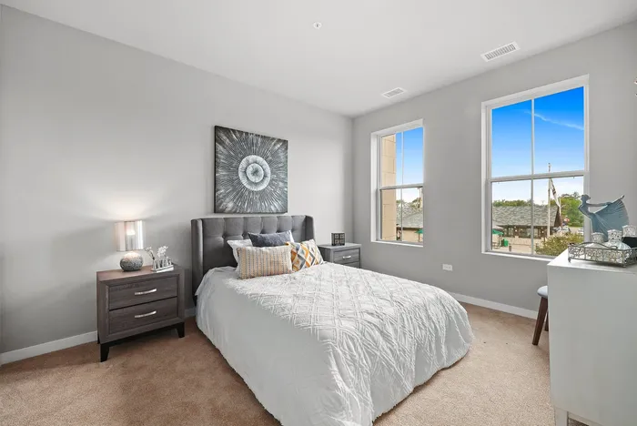 Bright and inviting bedroom with modern decor, featuring a plush bed, stylish artwork, and large windows with scenic views.