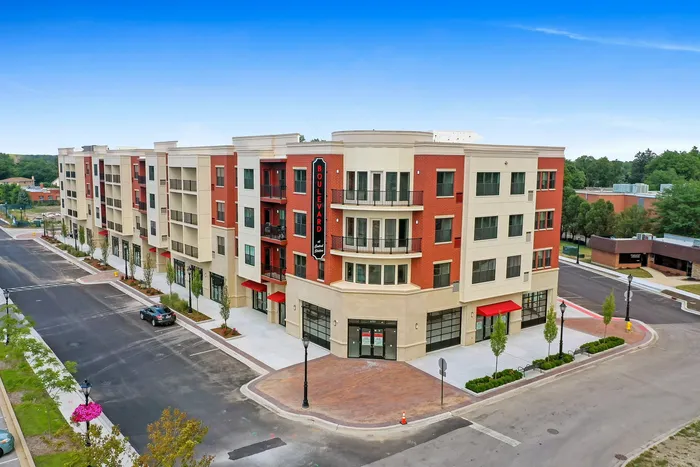 Modern urban apartment complex featuring elegant red brickwork, large windows, and stylish balconies, highlighting a vibrant city lifestyle.