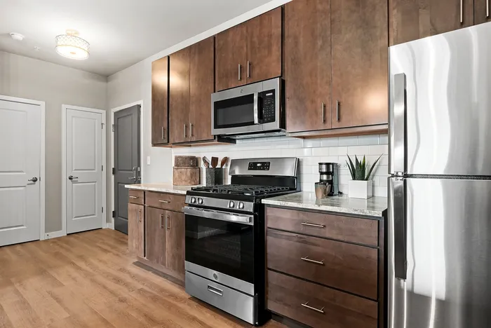 Modern kitchen featuring sleek stainless steel appliances, hardwood floors, and rich wooden cabinetry.