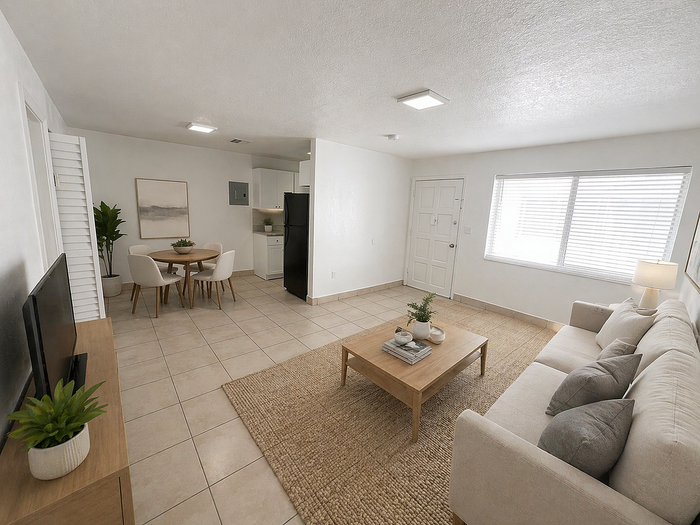 Bright, open-concept living room with elegant beige sofa, chic coffee table, and modern dining area adjacent to a sleek kitchen. Large window fills the space with natural light.