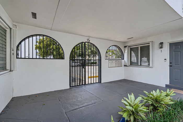 Inviting apartment entrance with modern gray door, stylish arch windows, and lush greenery for an elegant welcome.