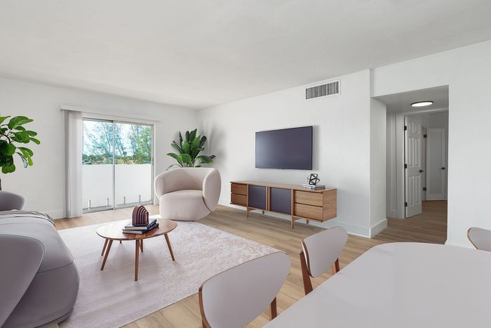 Elegant modern living room with sleek furniture, large sliding doors opening to a lush view, and stylish wood flooring.