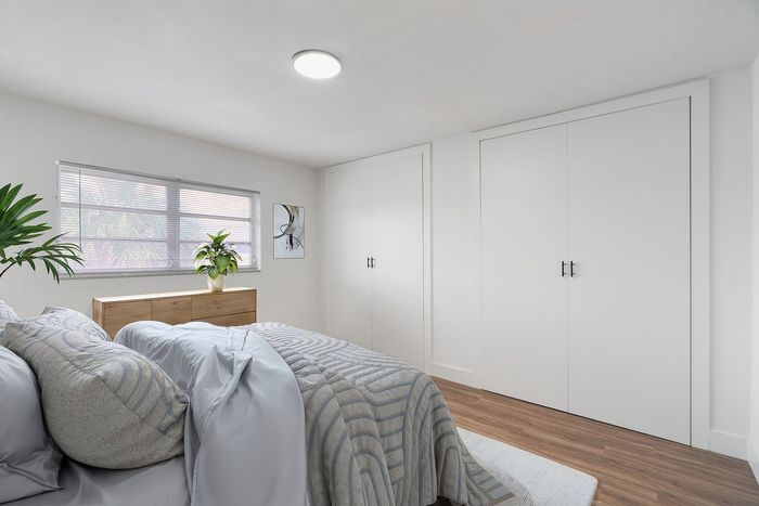 Bright and airy bedroom with modern decor, featuring a cozy bed, sleek wooden floor, and ample natural light through large windows.