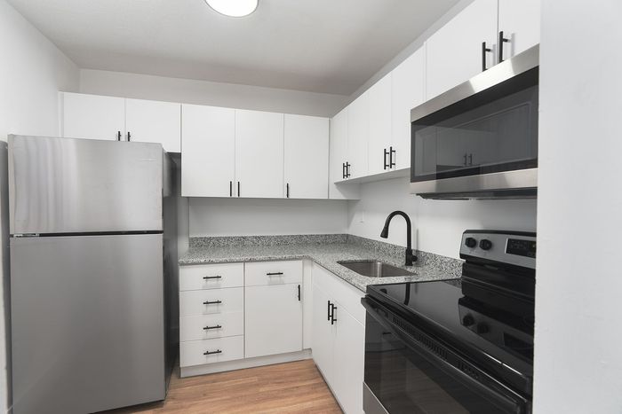 Modern kitchen with sleek stainless steel appliances, elegant granite countertops, and stylish white cabinetry.