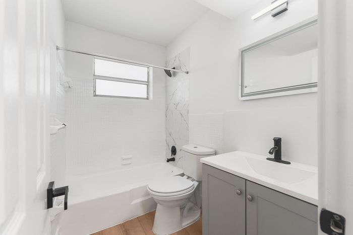 Sleek and modern bathroom with elegant marble accents, spacious bathtub, and contemporary fixtures.