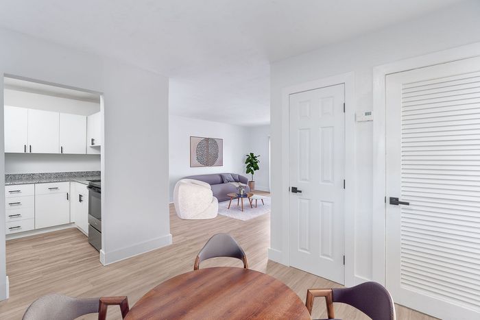 Bright, modern living space featuring a sleek kitchen with white cabinetry, cozy seating area with designer furniture, and stylish decor complementing the open-concept layout.