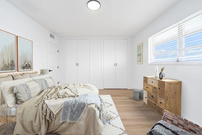 Bright and airy bedroom featuring cozy decor, elegant wooden furniture, and abundant natural light from large windows.