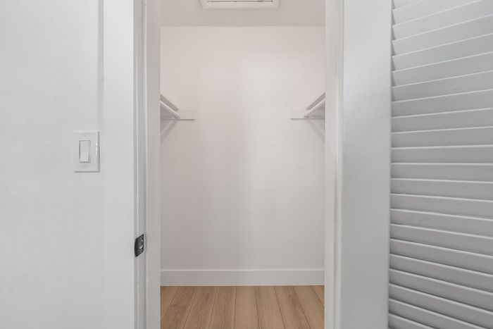 Spacious walk-in closet with elegant wood flooring and ample shelving, perfect for a well-organized wardrobe.