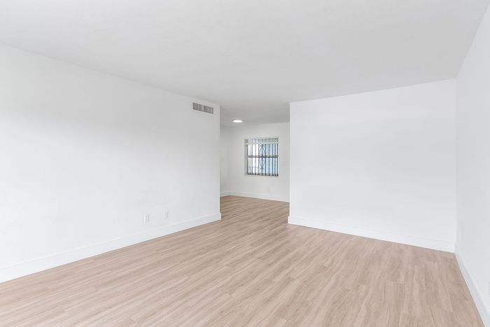 Bright and inviting open space with sleek wooden flooring and abundant natural light, perfect for flexible interior design opportunities.