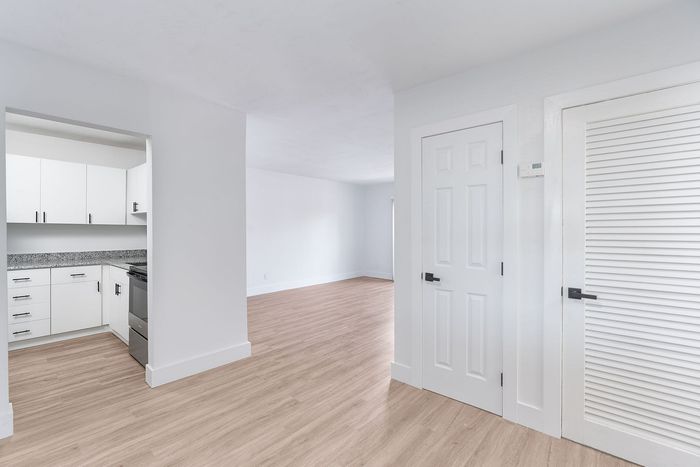 Bright and modern interior featuring a sleek white kitchen and open-concept living space with elegant wood flooring.
