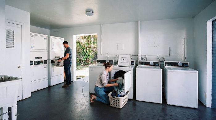 Modern laundry room with ample natural light, featuring multiple washers and dryers for convenient living.