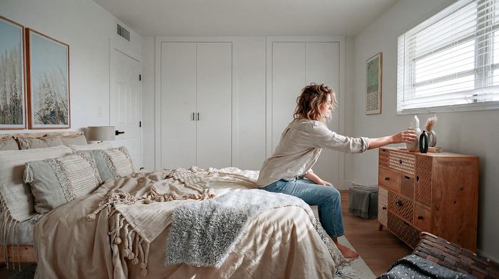 Elegant bedroom with cozy textiles, stylish decor, and natural light filtering through a window, offering a serene atmosphere.