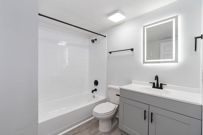 Modern and elegant bathroom featuring a sleek vanity with an illuminated mirror, classic white bathtub, and contemporary fixtures for a sophisticated look.