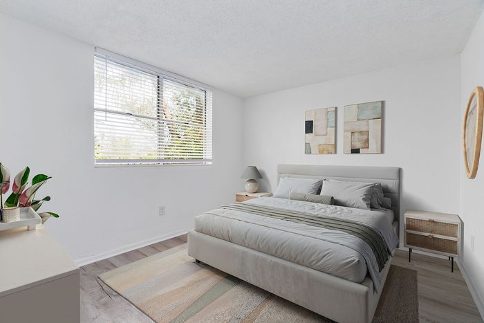 Bright and modern bedroom with floor-to-ceiling window, elegant decor, and plush queen bed for ultimate comfort.