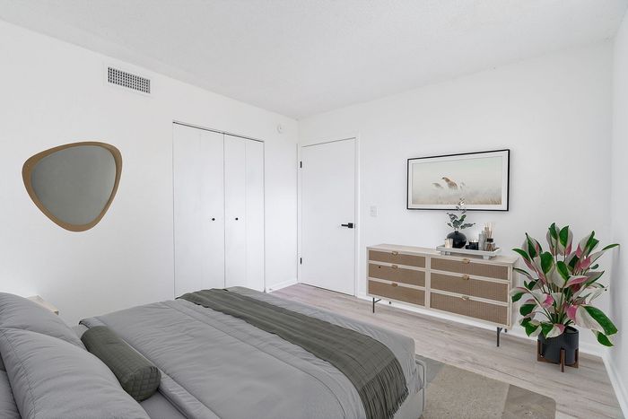 Elegant bedroom with a cozy bed, stylish decor, and ample closet space, complemented by natural light and modern furnishings.
