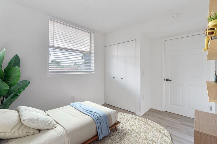 Bright and cozy bedroom with modern decor, featuring a comfortable single bed, light wooden flooring, and ample natural light from a large window.