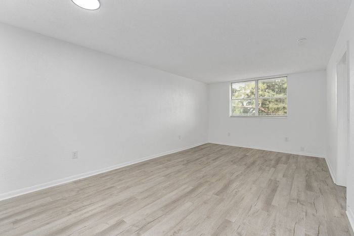 Bright and airy living space with elegant wood flooring and a large window offering natural light.