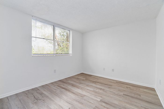 Bright, airy room with sleek wooden floors and a large window, perfect for natural light lovers.