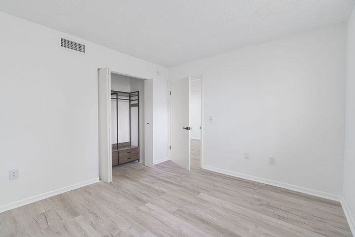 Bright and airy bedroom with elegant laminate flooring and spacious built-in closet.