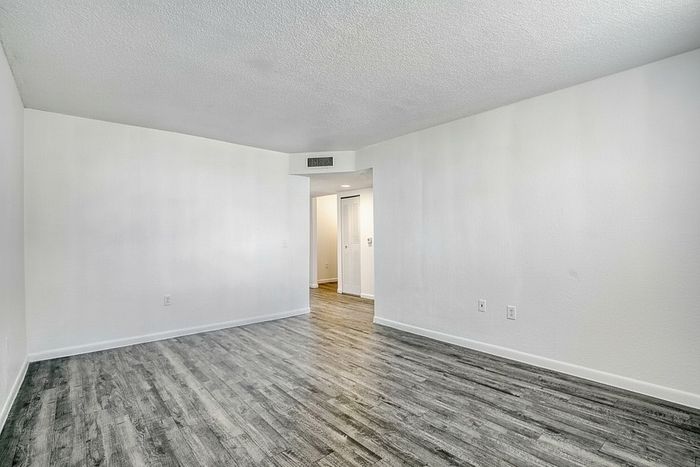 Elegant living area with modern hardwood flooring and bright white walls, offering a spacious and airy feel.