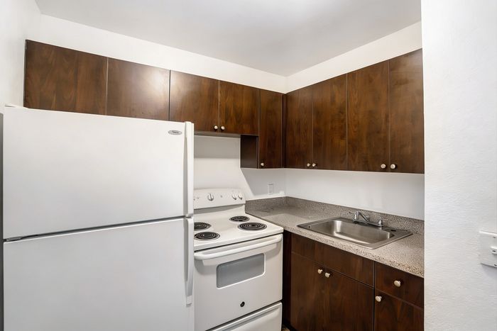Charming kitchen with sleek granite countertops, modern white appliances, and rich wood cabinetry for a warm, stylish appeal.