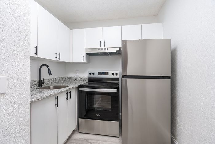 Modern kitchen with sleek stainless steel appliances, chic white cabinetry, and elegant granite countertops.