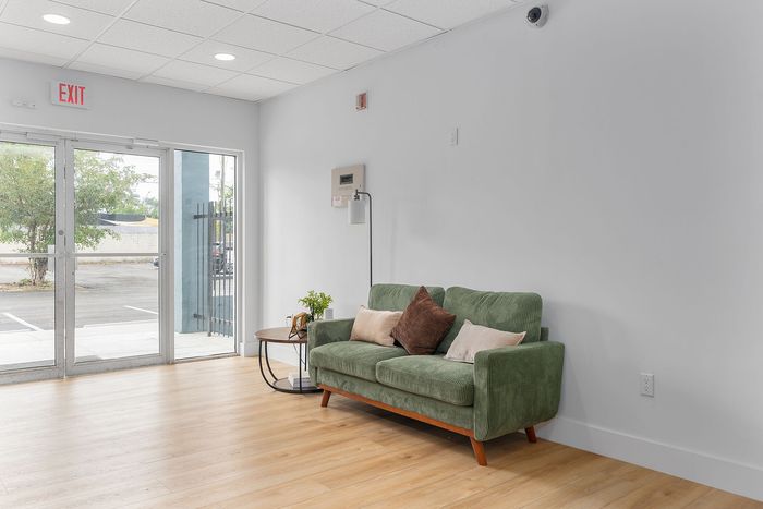 Bright and inviting lobby featuring a cozy green sofa and modern decor, perfect for relaxation.