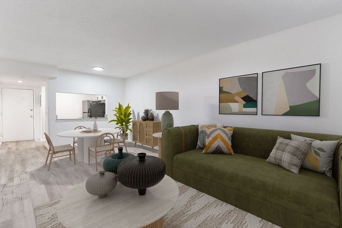 Modern living space featuring a chic green sofa, abstract art, and a stylish dining area with natural light and elegant decor.