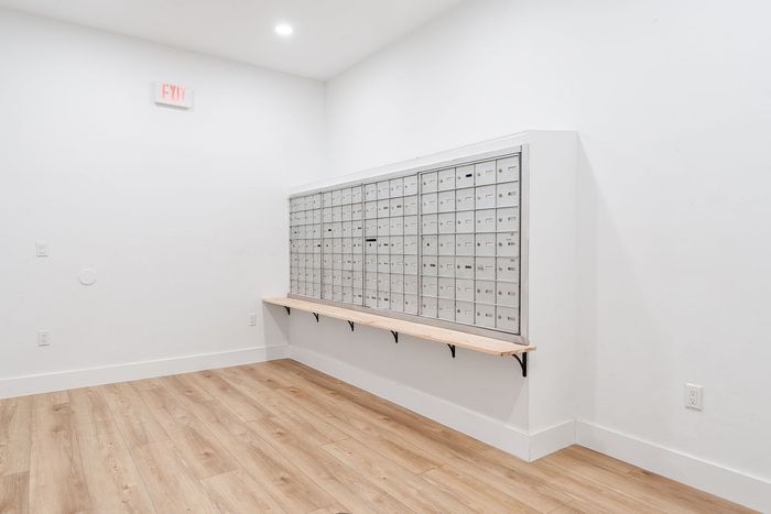 Modern mailroom featuring sleek mailboxes with a minimalist design and polished wooden flooring.