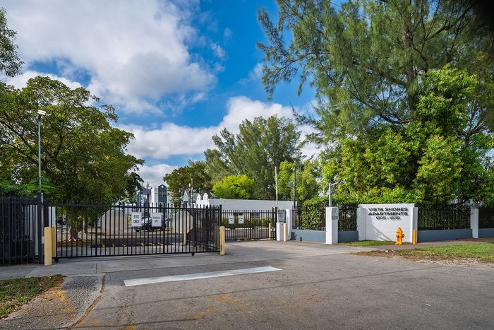 Inviting entrance to Vista Shores Apartments, surrounded by lush greenery and a clear blue sky, ensuring a warm welcome home.