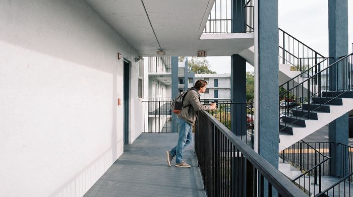 Contemporary apartment exterior featuring sleek railings, a spacious walkway, and architectural staircases under a clear sky.